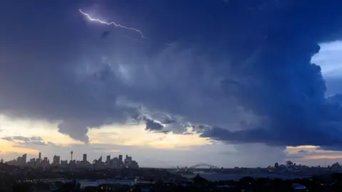 Mark Evans/Getty Images Lightning is seen over the city skyline as storm clouds gather